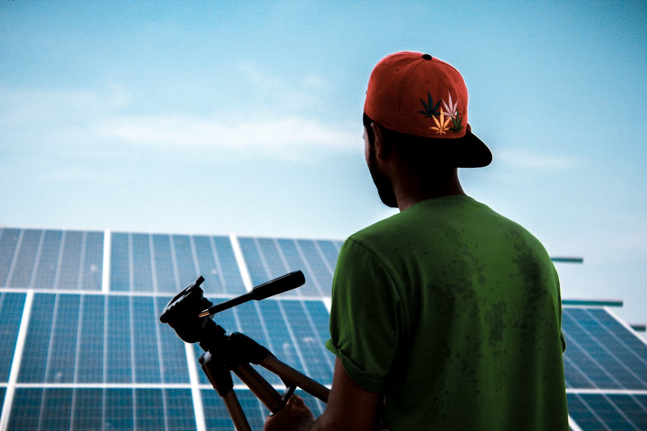 A person in a cap films a solar panel installation, promoting sustainable energy solutions.
