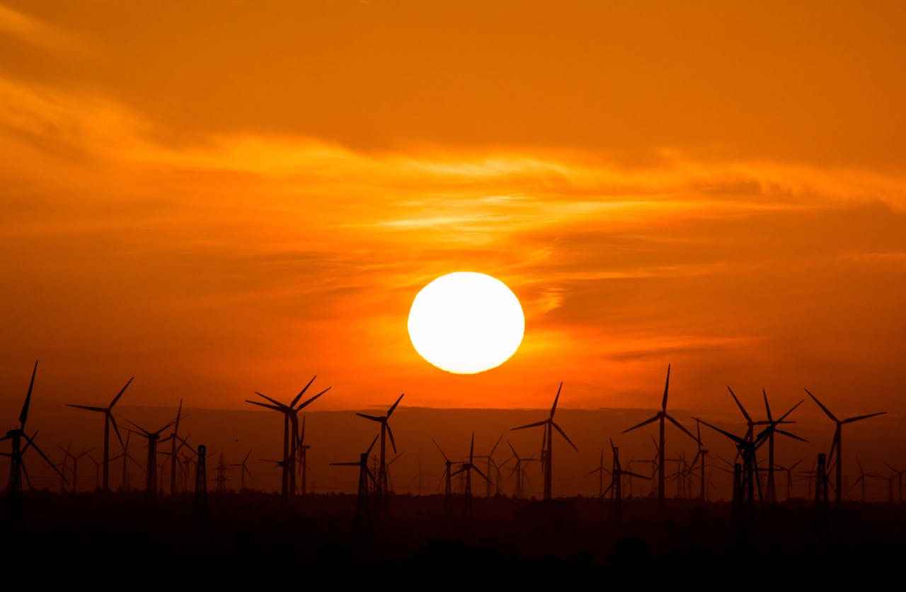 services-03 Wind turbines silhouetted against a stunning sunset, showcasing renewable energy in nature.